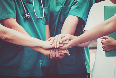 A group of hands are placed together in a team effort