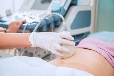 A health professional is using ultrasound equipment to detect a baby\&apos;s heartbeat