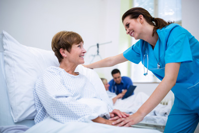 A patient is sitting in a hospital bed and smiling at a nurse