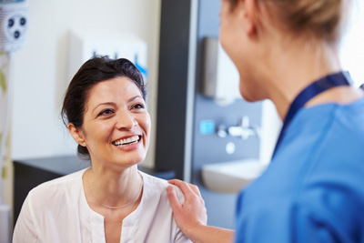 A patient and nurse are smiling at one another