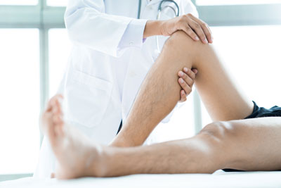 A health professional is assisting a patient with leg exercises