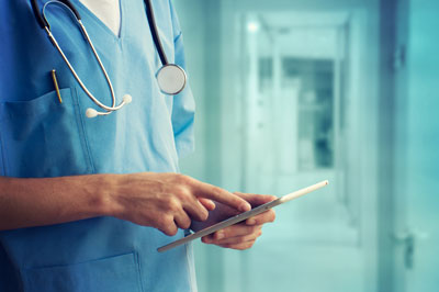 A medical professional is standing in the hospital hall and pointing at a clipboard