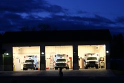 Three ambulance trucks are parked in garages